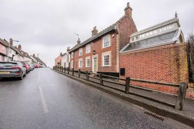 a street with cars parked on the side of a brick building at Lantern Cottage, Debenham in Stowmarket