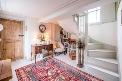 a room with a staircase with a desk and a clock at Lantern Cottage, Debenham in Stowmarket