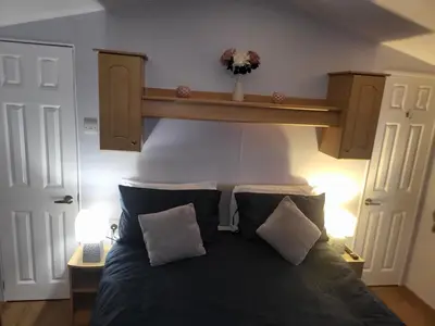 a bedroom with a large bed with a wooden headboard at Vacation Escape - Valley Farm -Clacton-on-sea - Holiday Park in Clacton-on-Sea