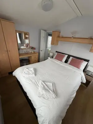 a bedroom with a large bed with white sheets and red pillows at Vacation Escape - Valley Farm -Clacton-on-sea - Holiday Park in Clacton-on-Sea
